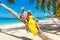 Young happy couple in hats sitting on a coconut tree on a sandy tropical beach. Travel and vacation concept