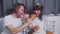 Young happy couple having fun while eating breakfast in bed. Man giving croissant to his wife