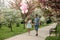 Young happy couple in love outdoors. Handsome man and beautiful woman on a walk in a spring blooming park. They keep