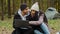 Young happy couple in love tourists sit outdoors in campsite look at laptop screen choose place to travel on electronic