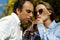 Young happy couple outdoors drinking cold drink from glass bottle with straw. Side view of man and woman drinking soft