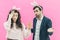 Young happy couple on the pink background. On the head is a rabbit ears. A young girl holding a carrot of small size in