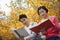 Young happy couple sitting on a park bench reading books, springtime in the park