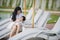 Young happy and cute Asian Chinese woman nursing daughter baby girl with formula bottle at holidays tropical resort swimming pool