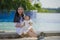 Young happy and cute Asian Chinese woman playing with daughter baby girl at holidays tropical resort swimming pool enjoying summer