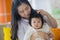 Young happy and cute Asian Korean woman playing and holding sweet expressive baby girl sitting at holidays resort in mother and