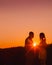 Young happy engaged couple silhouetted at sunset