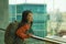 Young happy and excited Asian Japanese student woman with backpack at airport departure lounge watching aircraft through glass