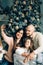 Young happy family of four taking a photo of themselves by a fireplace