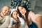 Young happy family of four taking a photo of themselves by a fireplace