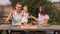 Young Happy Family Having Picnic In The Garden. Mom, Dad And Son Eating Pizza Outdoors