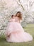 Young happy family, mom and daughter in beautiful evening festive long powdery pink color dresses. Woman holds little