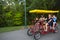 Young happy family riding a double surrey tandem bicycle together.