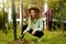 Young happy farmer woman in straw hat sitting in garden taking care of her plants and harvest. Young adult female