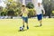 Young happy father and excited little 7 or 8 years old son playing together soccer football on city park garden running on grass k