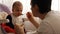 Young happy father feeds his son baby porridge.