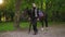 Young happy female horse rider is walking with brown horse with white spot on forehead in park during sunny day holding