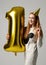 Young happy girl with huge gold digit one balloon as a present for birthday party