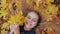 Young happy girl lies in autumn leaves and poses with maples leaves.