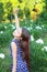 A young happy girl raising her hand up in relaxation, in a blue romper,