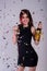 Young and happy girl with tinsel confetti in hands bottle of champange and wineglasses with champagne. New year`s