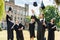 young happy graduated students throwing up graduation caps