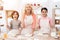 Young happy grandmother together with little happy grandchildren knead dough for cookies in kitchen.