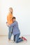 Young happy guy is kneeling and hugging his beloved woman thinking of another man posing on a white background. Unequal