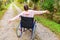 Young happy handicap woman in wheelchair on road in hospital park enjoying freedom. Paralyzed girl in invalid chair for disabled