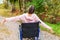 Young happy handicap woman in wheelchair on road in hospital park enjoying freedom. Paralyzed girl in invalid chair for disabled