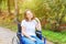 Young happy handicap woman in wheelchair on road in hospital park waiting for patient services. Paralyzed girl in