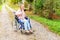 Young happy handicap woman in wheelchair on road in hospital park waiting for patient services. Paralyzed girl in invalid chair