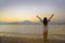 Young happy and healthy woman spreading arms free standing on sand beach looking at horizon sea water and volcano landscape on the