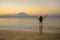 Young happy and healthy woman spreading arms free standing on sand beach looking at horizon sea water and volcano landscape on the