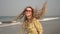 Young happy hippie woman with dreadlocks dancing and laughing on the sea beach.