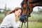 Young happy horsewoman with her bay stallion