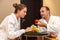 Young happy just married Caucasian couple in white bathrobes having fruits after spa on honeymoon. Man offers an apple to the woma