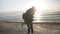 Young happy just married couple having fun on the beach playing piggy back during their honeymoon in slow motion -