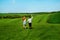 Young happy lovers running on meadow with green grass and blue s