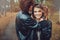 Young happy loving couple in leather jackets hugs outdoor on cozy walk in forest