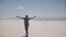 Young happy male tourist walking with arms open enjoying perfect road trip at sunny salt desert lake epic scenery.