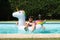 Young happy man on a big unicorn inflatable ring in a swimming pool