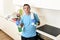 Young happy man holding washing detergent spray bottle and cloth in rubber gloves smiling