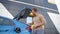 Young happy man install charger plug to electric and embrace his car while waiting till his electric car charge