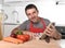 Young happy man at kitchen reading recipe book in apron learning cooking