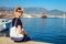 Young happy man looks at the Alanya port. Smiling traveller sitting by the sea. Vacation concept