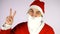 Young happy man in santa claus suit isolated over white wall showing peace gesture