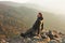 Young and happy man sitting at the top of the mountain. Landscape view of misty autumn mountain hills and man silhouette