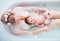 Young happy mother with newborn baby girl, daughter in floral milk bath