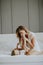 Young happy mother playing in a white bed enjoying a sunny morning in a modern home bedroom